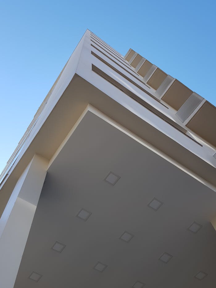 A low-angle view of a modern building showcasing geometric design against a clear blue sky.